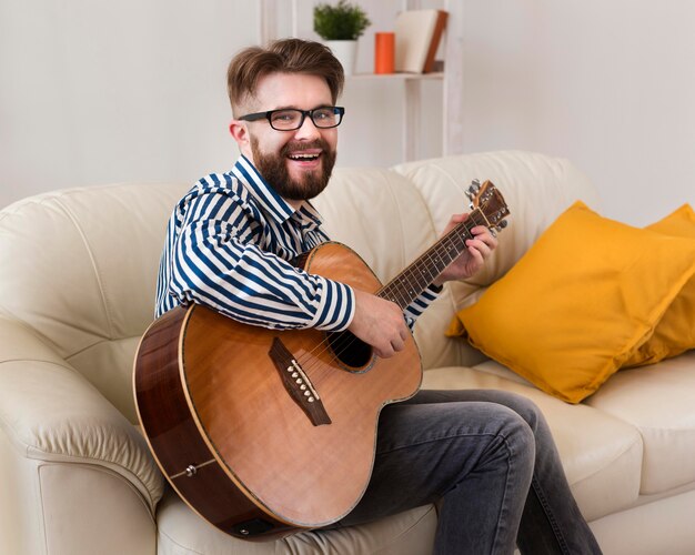 Smiley man on sofa playing guitar