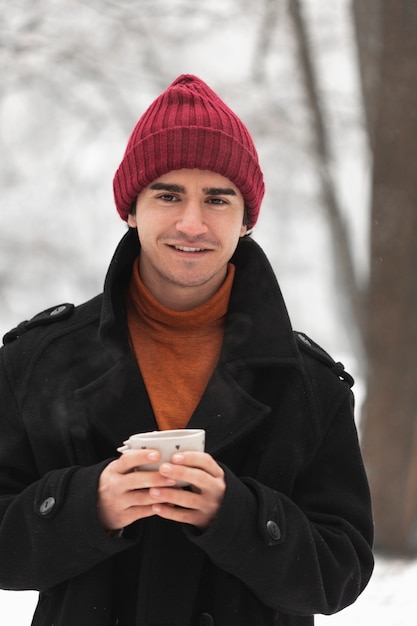 Foto gratuita uomo di smiley che porta cappello rosso e che tiene tazza di tè