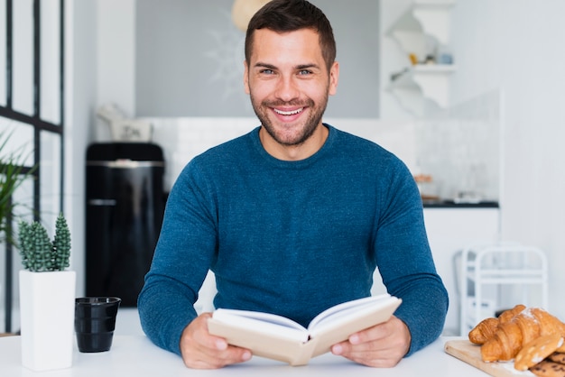 Smiley man with book in hand at home