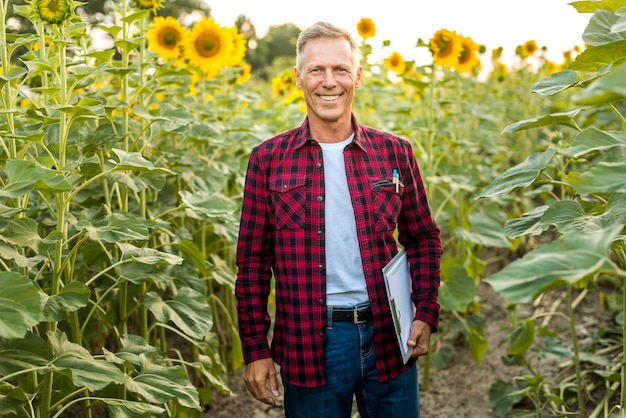 Foto gratuita uomo di smiley con una lavagna per appunti in un campo