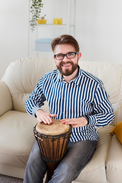 Free photo smiley man with drum on sofa