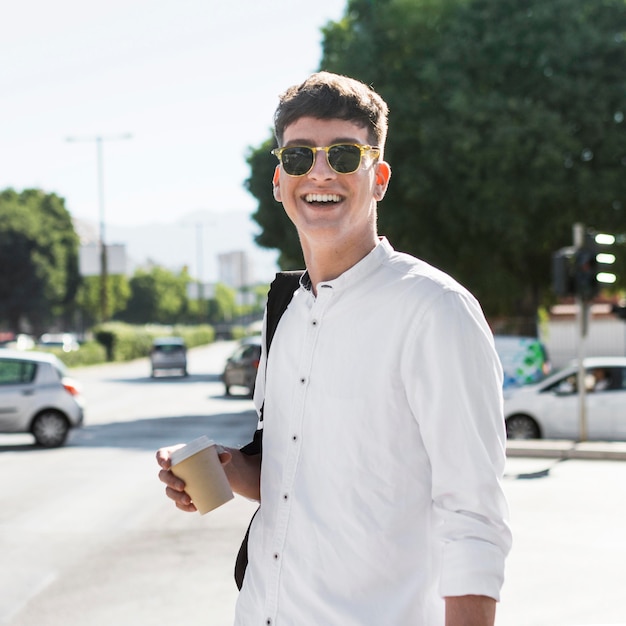 Smiley man with sunglasses having coffee outdoors in the city