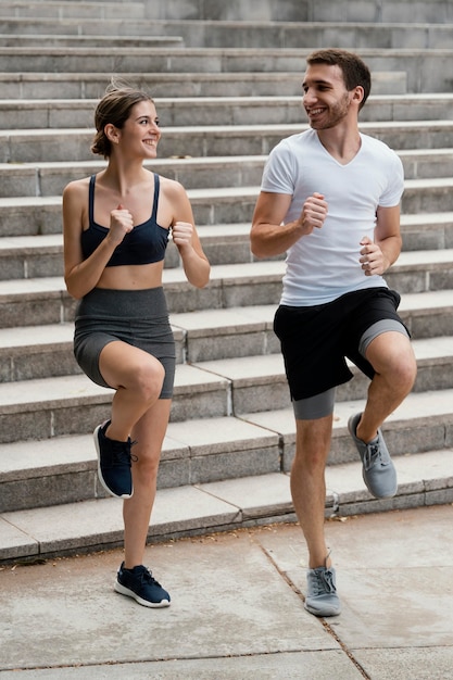 Smiley man and woman exercising on steps