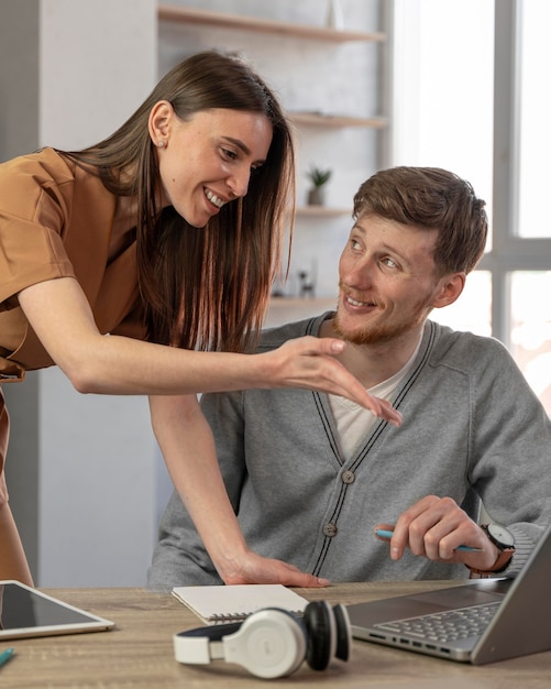 Smiley man and woman working with laptop and headphones