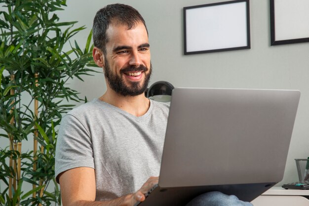 Smiley man working from home on laptop