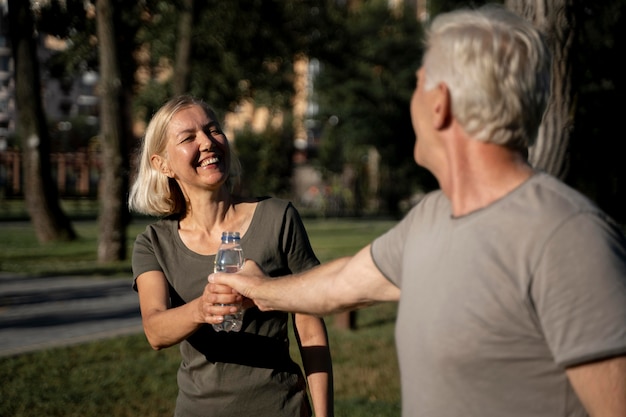 Smiley mature couple drinking water outdoors