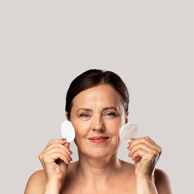 Smiley mature woman posing with cotton pads for make-up removal and copy space