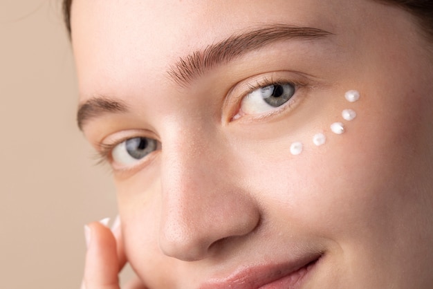 Foto gratuita modello di smiley con crema per gli occhi da vicino
