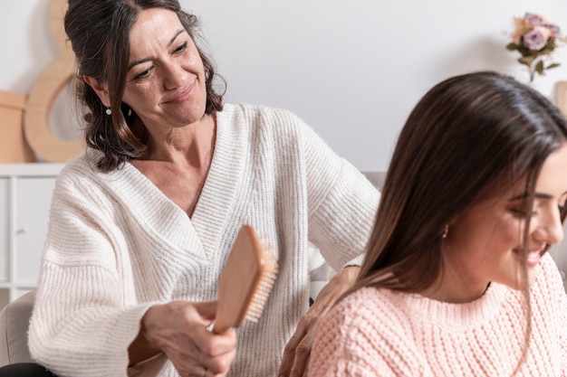 Smiley mom combing daughter hair