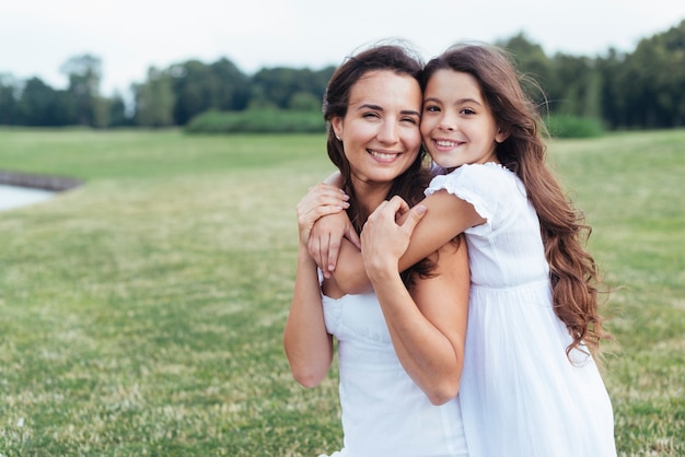 Smiley mother and daughter hugging outdoors