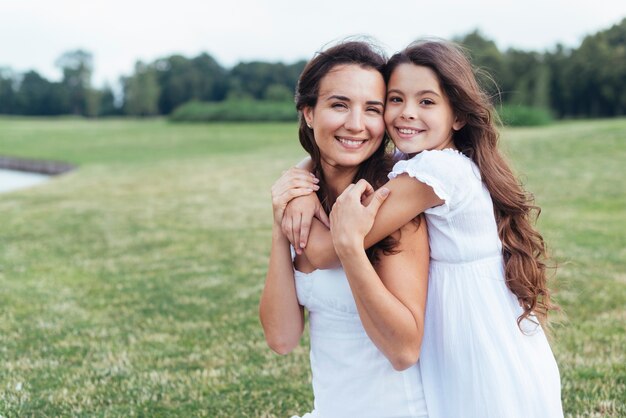 Smiley mother and daughter hugging outdoors