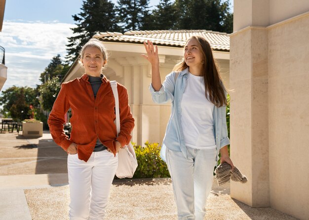 Smiley mother and daughter walking front view