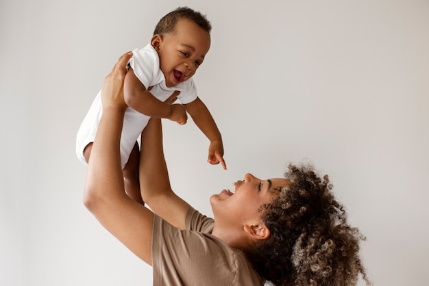 Foto gratuita vista laterale del bambino della holding della madre di smiley