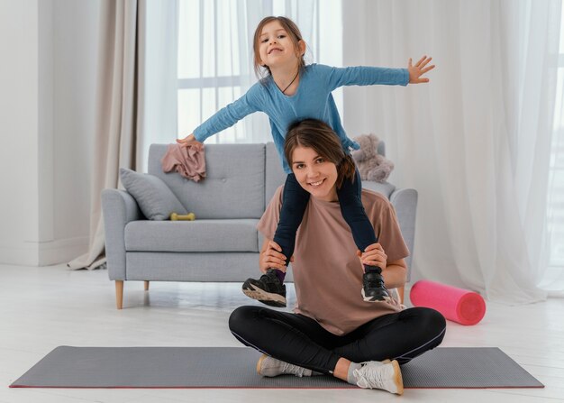 Foto gratuita ragazza della holding della madre di smiley sulle spalle