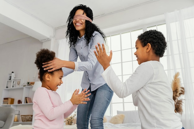 Free photo smiley mother playing with her children at home while blindfolded