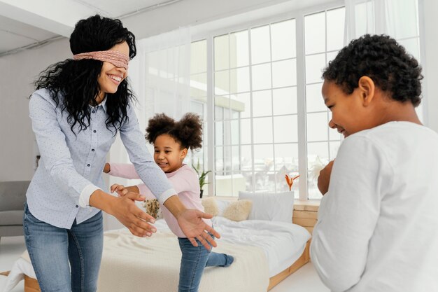 Smiley mother playing with her children at home