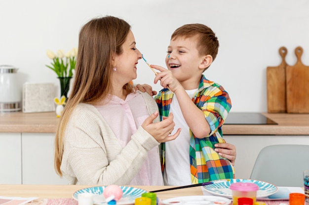 Smiley mother and son painting eggs