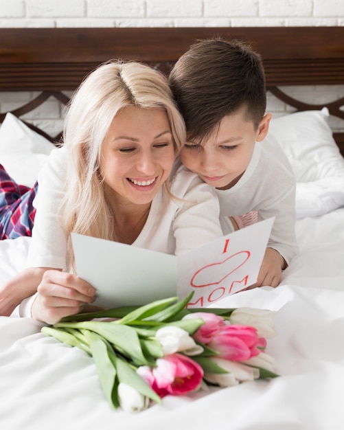 Улыбающаяся мама и сын читают поздравительную открытку