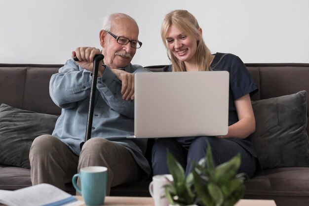 Smiley old man and nurse using laptop