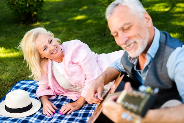 Free photo smiley old man playing guitar at the picnic