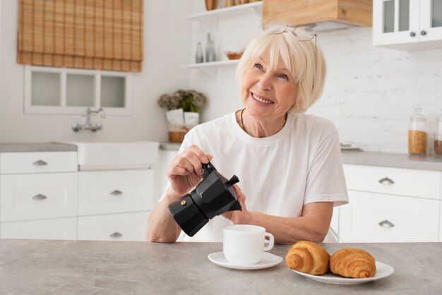 Smiley old woman holding the kettle