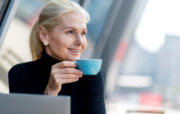 작업하는 동안 야외에서 커피를 마시고 웃는 이전 비즈니스 여성