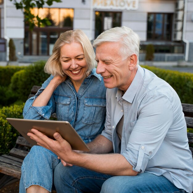 Smiley older couple looking at tablet in the city
