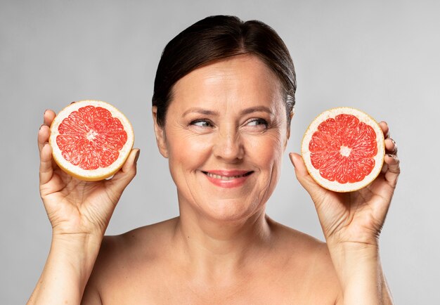 Smiley older woman holding half of grapefruit in each hand