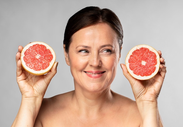 Бесплатное фото Смайлик пожилая женщина держит в каждой руке половину грейпфрута