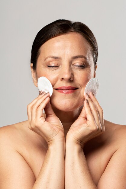 Smiley older woman posing with cotton pads for make-up removal