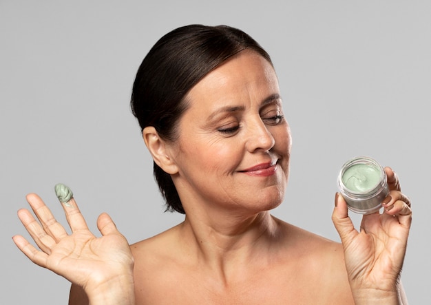 Smiley older woman using face mask