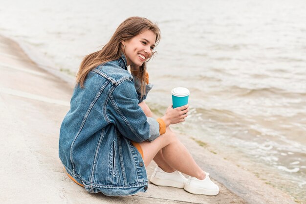 Smiley oman with coffee at seaside