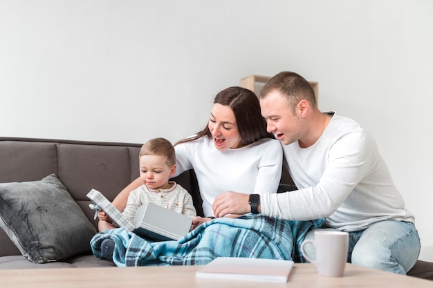 Free photo smiley parents on the couch with baby