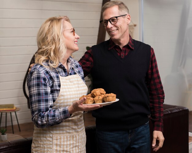 Free photo smiley parents holding plate with muffins