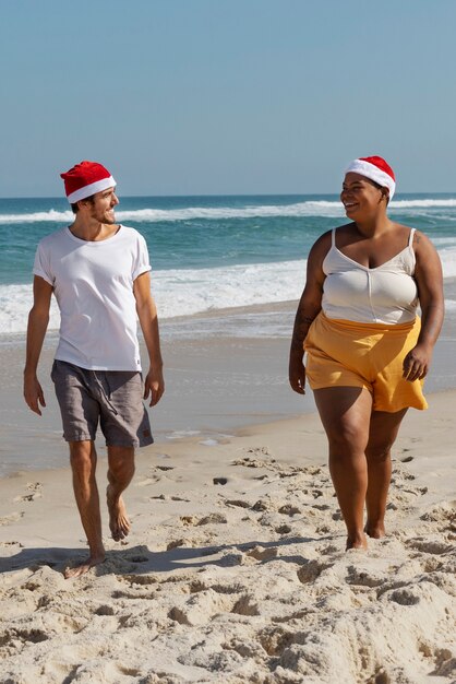 Gente sorridente che cammina sul colpo pieno della spiaggia