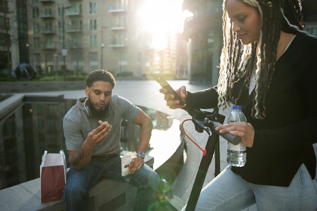 Foto gratuita persone sorridenti con scooter elettrico all'aperto