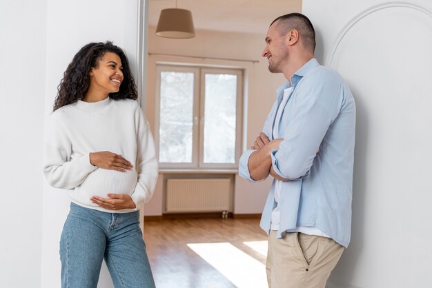 Smiley pregnant couple standing outside new house