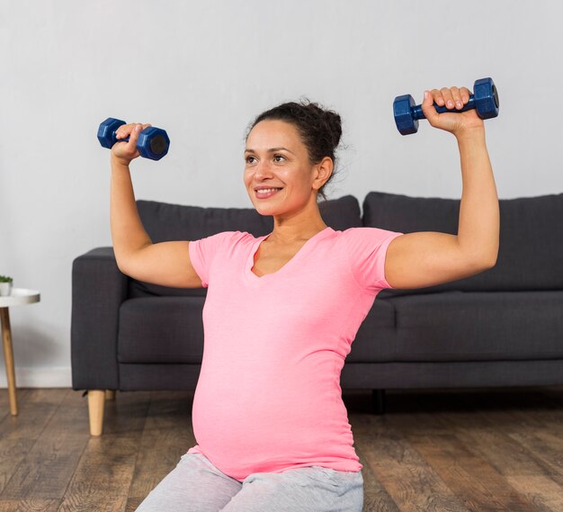 Smiley pregnant woman exercising with weights