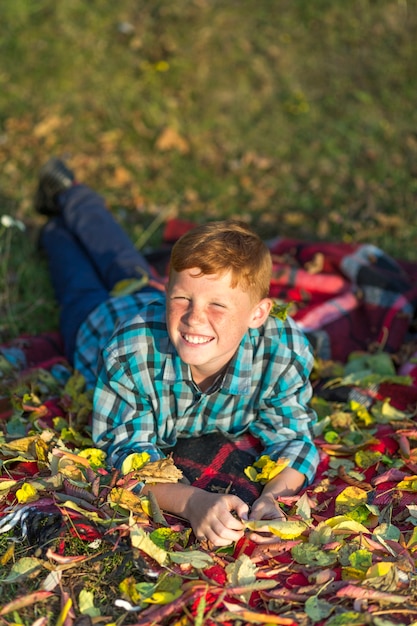 Free photo smiley redhead boy sitting on a picnic blanket