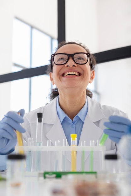 Free photo smiley scientist holding tubes medium shot