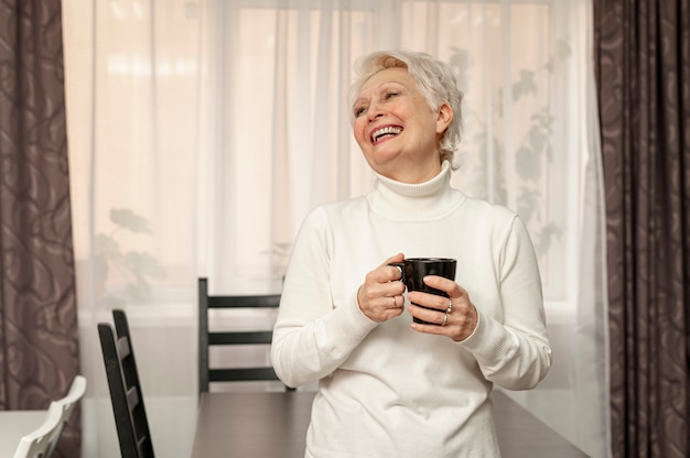 一杯のコーヒーを保持しているスマイリーシニア女性