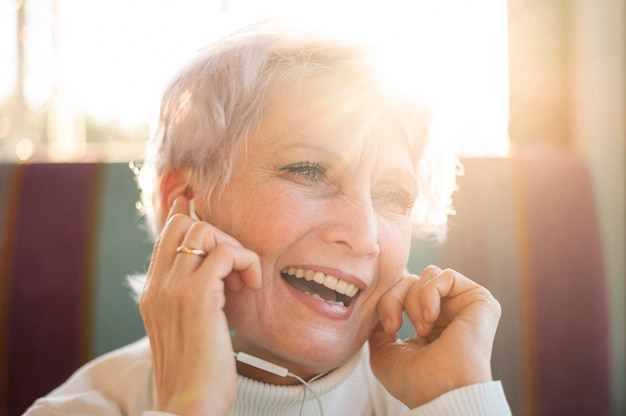 Free photo smiley senior female listening music