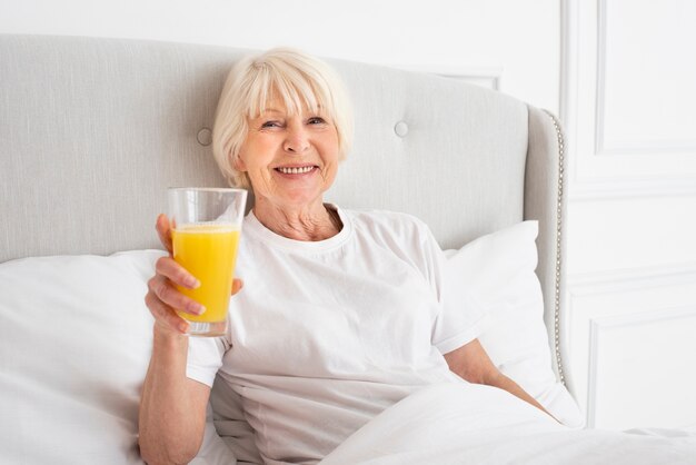 Smiley senior holding a glass with juice