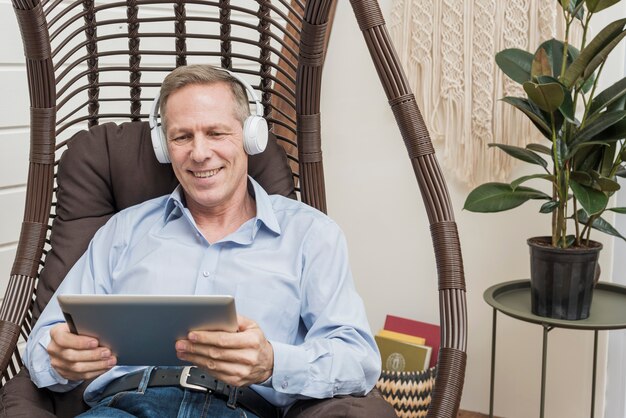 Smiley senior man listening to music though headphones