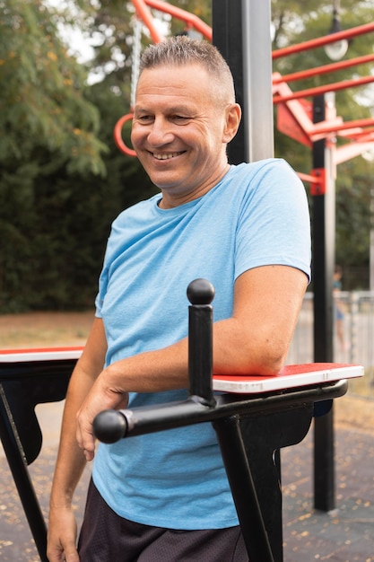 Free photo smiley senior man posing while working out outdoors