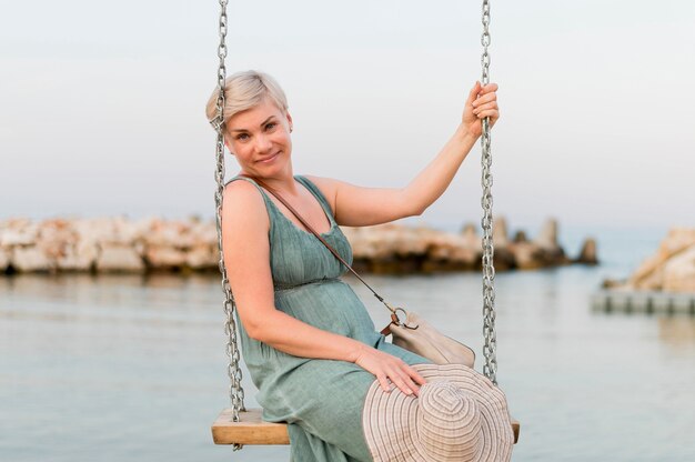 Smiley senior tourist woman at the beach in swing