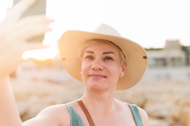 Smiley senior tourist woman taking selfie at the beach