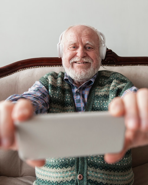 Free photo smiley senior watching video music on mobile