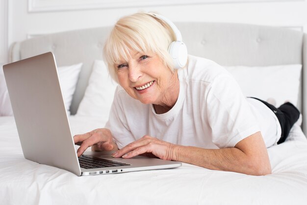Smiley senior with headphones and laptop