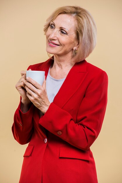一杯のコーヒーを押しながらよそ見スマイリー年配の女性